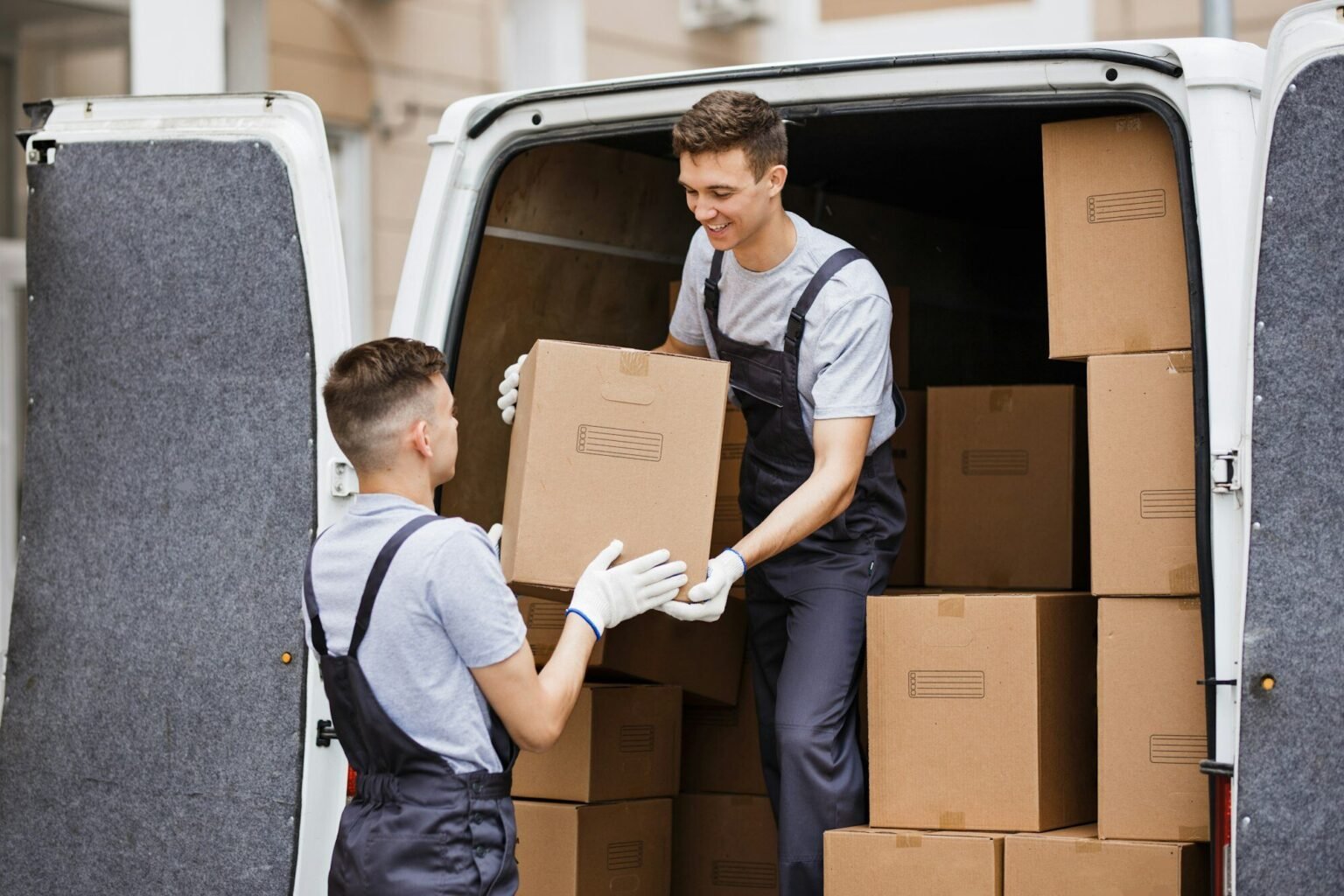 two-young-handsome-movers-wearing-uniforms-are-unloading-the-van-full-of-boxes-house-move-mover-1536x1024